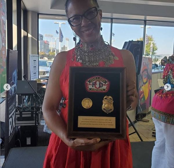 A woman holding up a plaque with two badges on it.