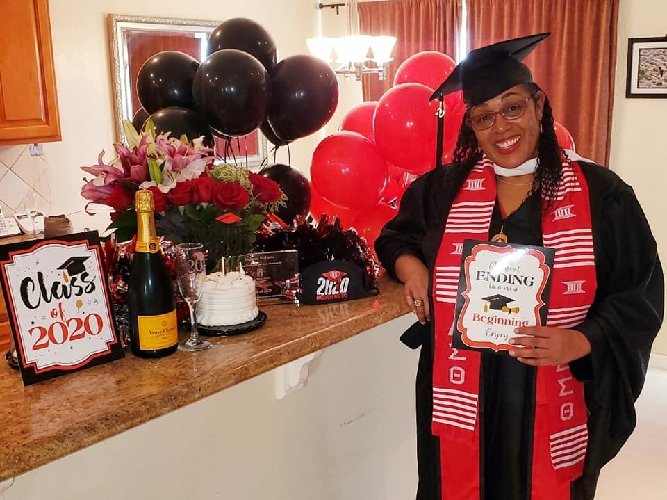 A woman in graduation attire holding her book.