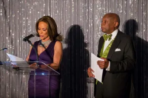 Two presenters at podium with glittering backdrop