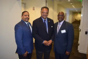 Three men in suits smiling in hallway